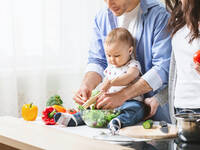 Familie mit kleinem Kind bereitet gemeinsam Salat zu