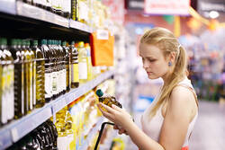 Frau im Supermarkt mit Olivenölflasche