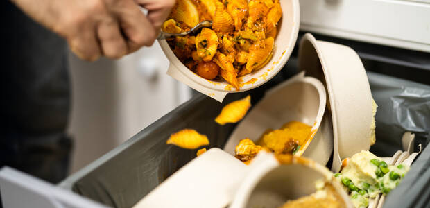 Nudeln werden von Teller in den Müll geschüttet.