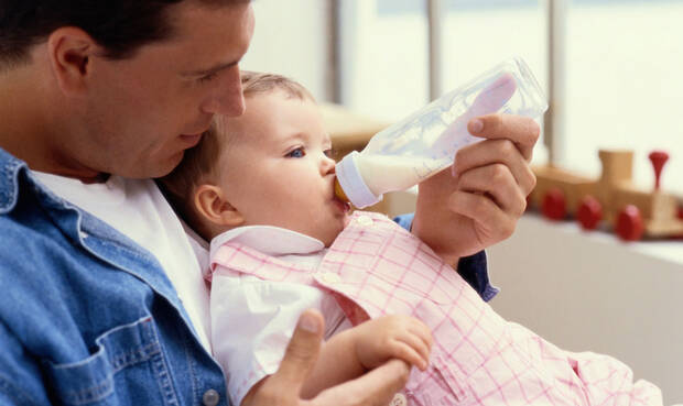 Vater füttert Baby die Flasche.