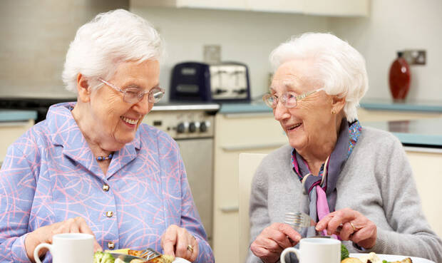 Seniorinnen sitzen am Tisch und essen.