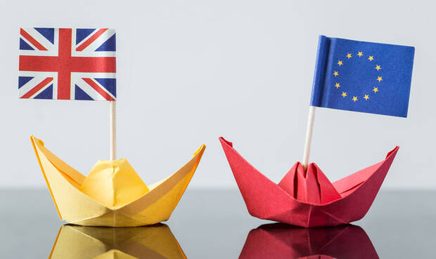 Zwei Papierschiffe und den Flaggen der EU und Großbritanniens.