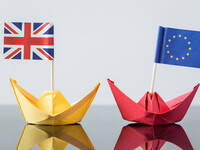 Zwei Papierschiffe und den Flaggen der EU und Großbritanniens.