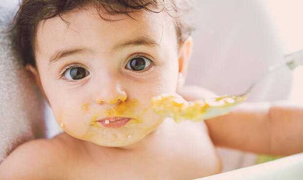 Baby wird mit Brei gefüttert.