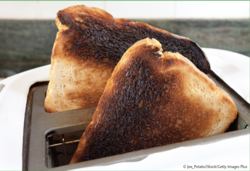 Nicht nur Chips, Cracker und Kekse enthalten Acrylamid, sondern auch zu stark gebackener Toast und dunkel-verbrannte Brotrinde. Dunkel-verbranntes Toastbrot im Toaster.